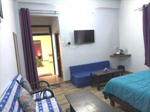 uma sala de estar com um sofá azul e uma televisão em Foreigners' Inn em Varanasi