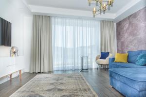 a living room with a blue couch in front of a window at Million Sunsets Luxury Apartments in St Paul's Bay
