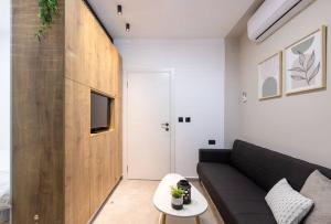 a living room with a black couch and a tv at Unique Central Old Town Studio Apartment in Beer Sheva