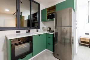 a kitchen with green cabinets and a refrigerator at Unique Central Old Town Studio Apartment in Beer Sheva