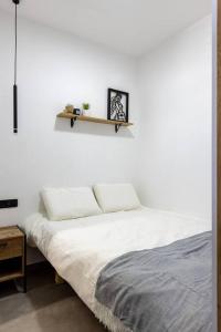 a white bedroom with a bed and a shelf on the wall at Unique Central Old Town Studio Apartment in Beer Sheva