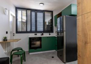 een keuken met groene kasten en een koelkast bij Unique Central Old Town Studio Apartment in Beer Sheva