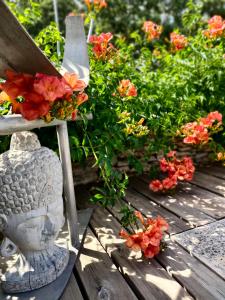 une statue en pierre assise sur un banc en bois avec des fleurs dans l'établissement Villa Cabrida, à Cabrières-dʼAvignon