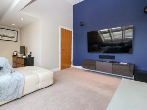 a bedroom with a bed and a tv on a blue wall at Sandy House in Rhosneigr