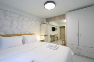 Fully renovated underground flat in Pagrati في أثينا: غرفة نوم بها سرير أبيض كبير وطاولة