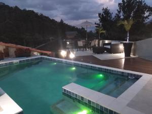 una piscina por la noche con mesa y sillas en Pousada dos Sonhos - MP, en Miguel Pereira