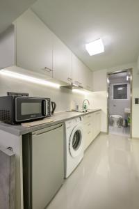 Fully renovated underground flat in Pagrati في أثينا: مطبخ مع غسالة ملابس وميكروويف