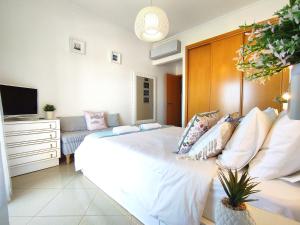 ein Schlafzimmer mit einem großen weißen Bett und einem TV in der Unterkunft AlbufeiraOrada II by Be Cherish in Albufeira