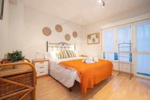 een slaapkamer met een groot bed en een oranje deken bij Brizal Apartamento in Gijón