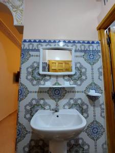 La salle de bains est pourvue d'un lavabo et d'un miroir mural. dans l'établissement RESIDENCE ABOU YASSINE, à Dakhla