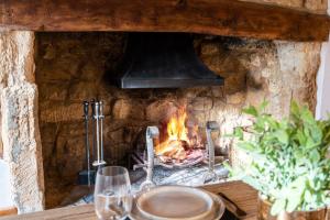 a stone fireplace with a stove with a fire at The Landers in Cheltenham