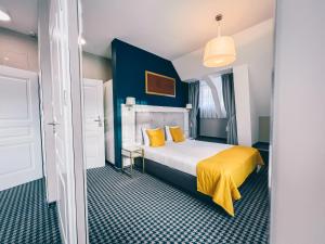 Habitación de hotel con cama con sábanas amarillas y paredes azules. en Villa Art Novis, en Wroclaw