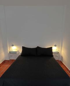 1 dormitorio con 1 cama negra y 2 lámparas en Oasis en pleno Nuñez en Buenos Aires