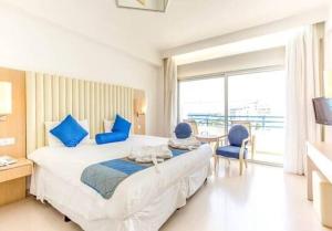 a bedroom with a large bed with blue pillows at Vrissiana Boutique Beach Hotel in Protaras