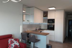 uma cozinha com armários brancos e um sofá vermelho em Apartment Vista Oasis with Pool and Terrace em Trogir
