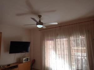 sala de estar con ventilador de techo y ventana en Apartamento 3 habitaciones centro de Torredembarra en Torredembarra