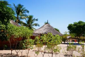 a couple of huts on a beach with trees at Campement Kaymba Lodge in Kachiouane