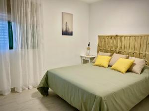 sypialnia z dużym łóżkiem z 2 żółtymi poduszkami w obiekcie Apartamento Las Olas • Playa del Inglés w mieście Playa del Ingles