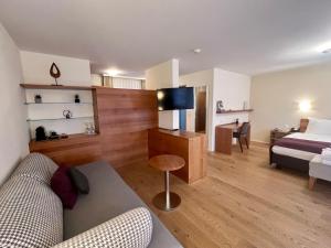 ein Wohnzimmer mit einem Sofa, einem Bett und einem TV in der Unterkunft Solbadhotel Sigriswil in Sigriswil