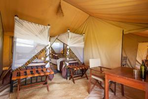 Gnu Ndutu Camp في Sinoni: غرفة نوم بسريرين في خيمة
