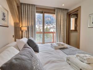 a bedroom with a large white bed with a window at Chalet Morzine, 7 pièces, 12 personnes - FR-1-627-20 in Morzine