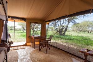 Sinoni的住宿－Gnu Ndutu Camp，帐篷内的桌子,享有田野美景