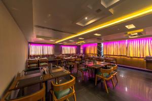 un ristorante con tavoli, sedie e luci viola di Hotel Tamizh Park a Pondicherry