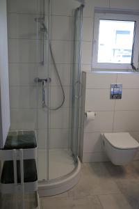 uma casa de banho com um chuveiro, um WC e uma janela. em Apartament Niechorze em Niechorze