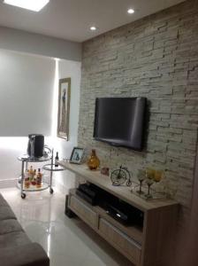 soggiorno con TV a schermo piatto su un muro di mattoni di Apartamento fino e decorado. a Lauro de Freitas