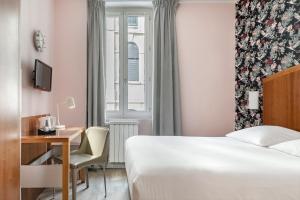 トゥーロンにあるGrand Hôtel Dauphiné, Boutique Hôtel & Suitesのベッド、デスク、窓が備わるホテルルームです。