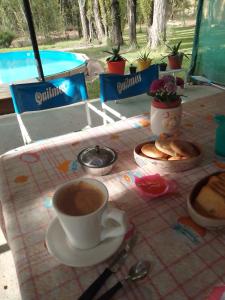 una mesa con una taza de café y galletas. en Nuestro Hogar en Malargüe