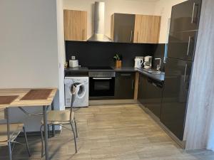 a kitchen with black appliances and a table with chairs at Sleep & Living FeWo Forst in Forst