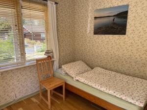 łóżko w pokoju z krzesłem i oknem w obiekcie typical Swedish cosy holiday house in Målilla, Småland w mieście Målilla