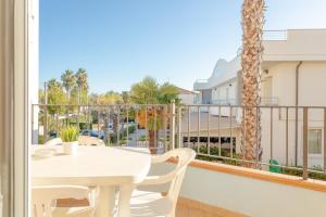 balkon z białym stołem i krzesłami oraz palmą w obiekcie Residence Il Triangolo w mieście Roseto degli Abruzzi