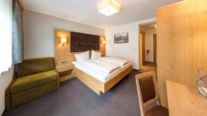 レルモースにあるBIRKENHOF - Premium Apart & Suitesのベッドと椅子付きのホテルルーム