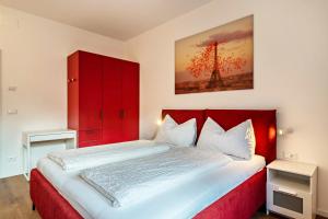 a bedroom with a red bed and a red cabinet at Central Suite Meran in Merano