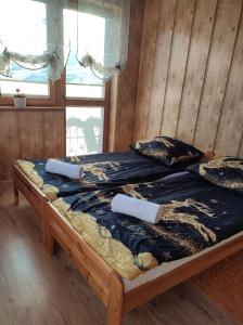 a bed in a wooden room with two pillows on it at Pokoje na Wierchu in Biały Dunajec