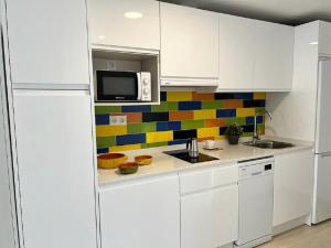 una cucina con armadietti bianchi e una parete di piastrelle colorate. di Bnbook Medea Apartments 2 a Fuengirola