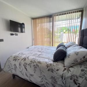 1 dormitorio con cama con almohadas y ventana en Departamento Edificio Aqua Pucón en Pucón