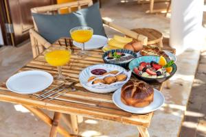 una mesa de madera con platos de comida y vasos de zumo de naranja en Boutique Hotel Wanapa en Kralendijk
