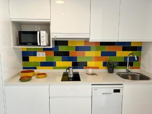 una cocina con armarios blancos y una pared colorida de azulejos. en Bnbook Medea Apartments 2, en Fuengirola