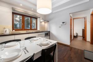 a dining room with a white table and a kitchen at RentPlanet - Śpiący Rycerz in Zakopane