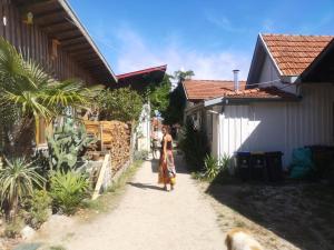 a woman walking down a path between two buildings at La cabane du Truquet in Lège-Cap-Ferret
