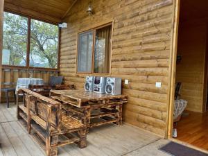 a porch of a log cabin with a table and speakers at Wooden House Ashuri in Veltaurtkari