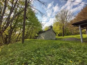 an old stone church on a grassy hill with trees at Wooden House Ashuri in Veltaurtkari