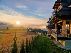 a sunset over a field next to a house at Domki Pod Tatrami in Rzepiska