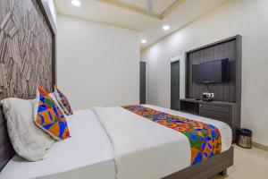 1 dormitorio con 1 cama grande y TV en FabExpress Pearl Villa, en Ahmedabad