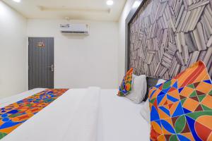 Un dormitorio con una cama blanca con una pared de colores estampados en FabExpress Pearl Villa, en Ahmedabad
