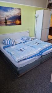 ein Bett mit blauer Bettwäsche und ein Gemälde an der Wand in der Unterkunft Das Ferienhaus am Ostseestrand in Gager