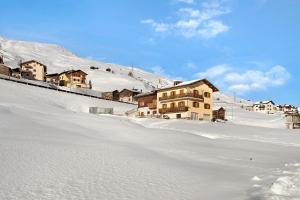 un groupe de maisons au sommet d'une montagne enneigée dans l'établissement Appartamento Presot, à Livigno